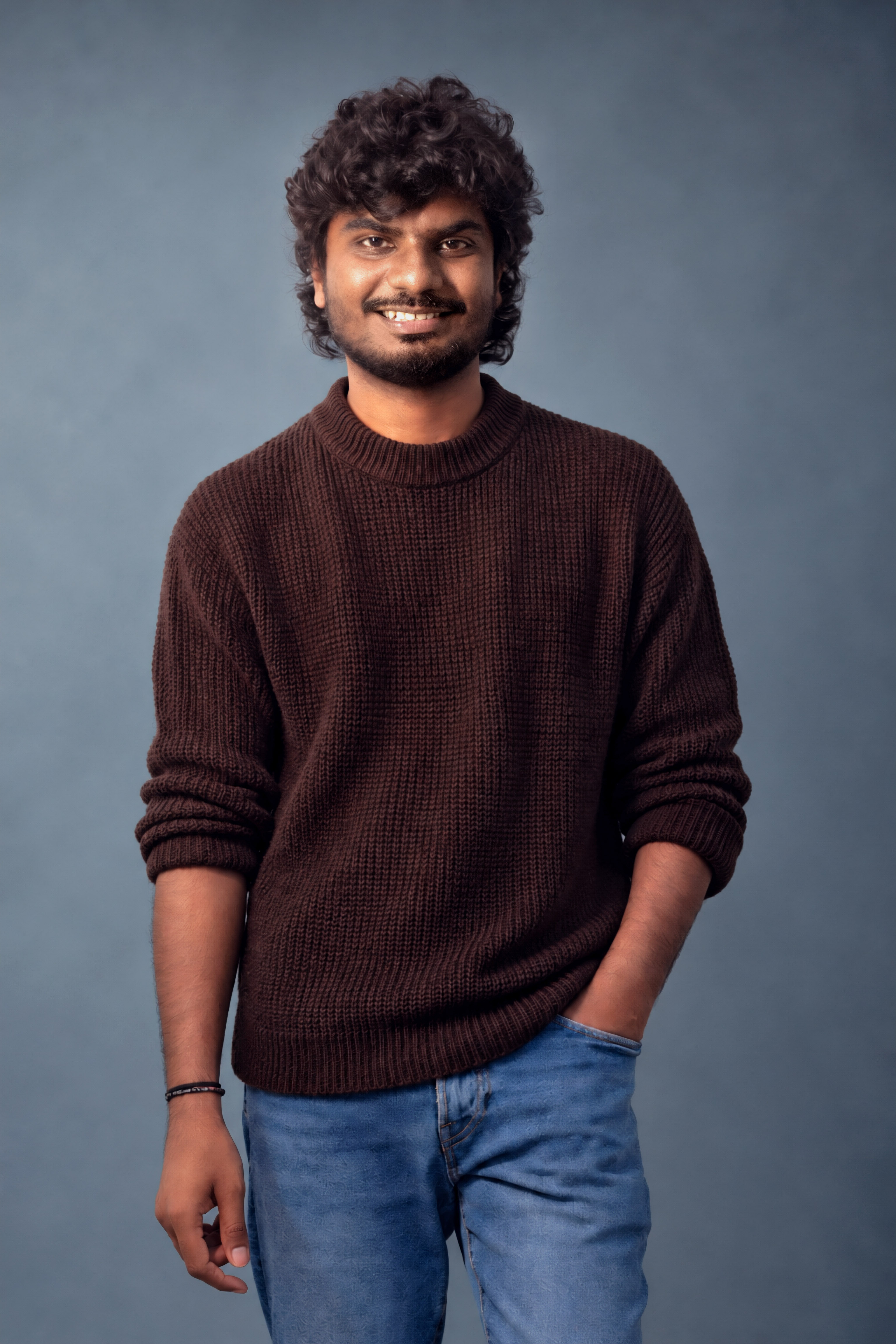 Relaxed three-quarter portrait, hand in pocket, smiling warmly